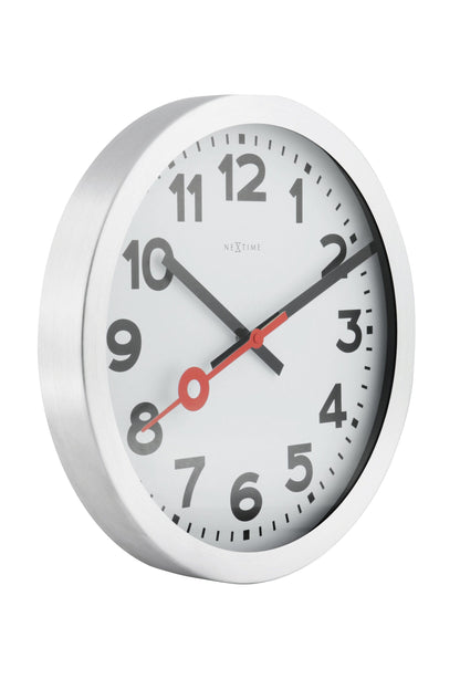 NeXtime Clocks aluminum station number wall or table clock showing a modern design with black clock hands and white dial.