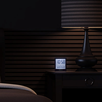 NeXtime digital alarm clock with LED display, compact size, black design, and "Wake Up" feature, placed on a bedside table.