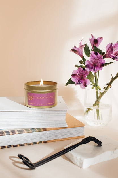 Flambé Fleuri Enchanted Rose Candle in a decorative tin with a floral design, emitting a soft, warm glow.